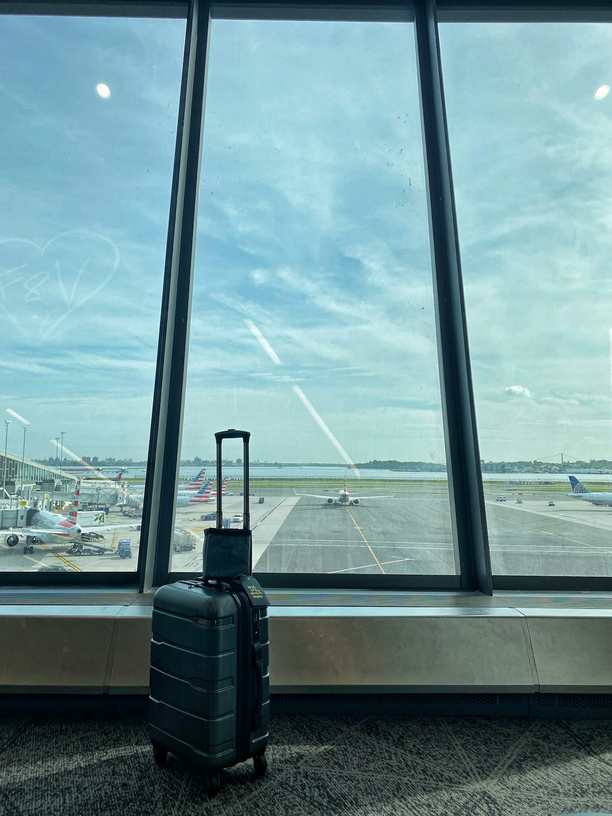 Suitcase waiting by an airport window with planes on the runway