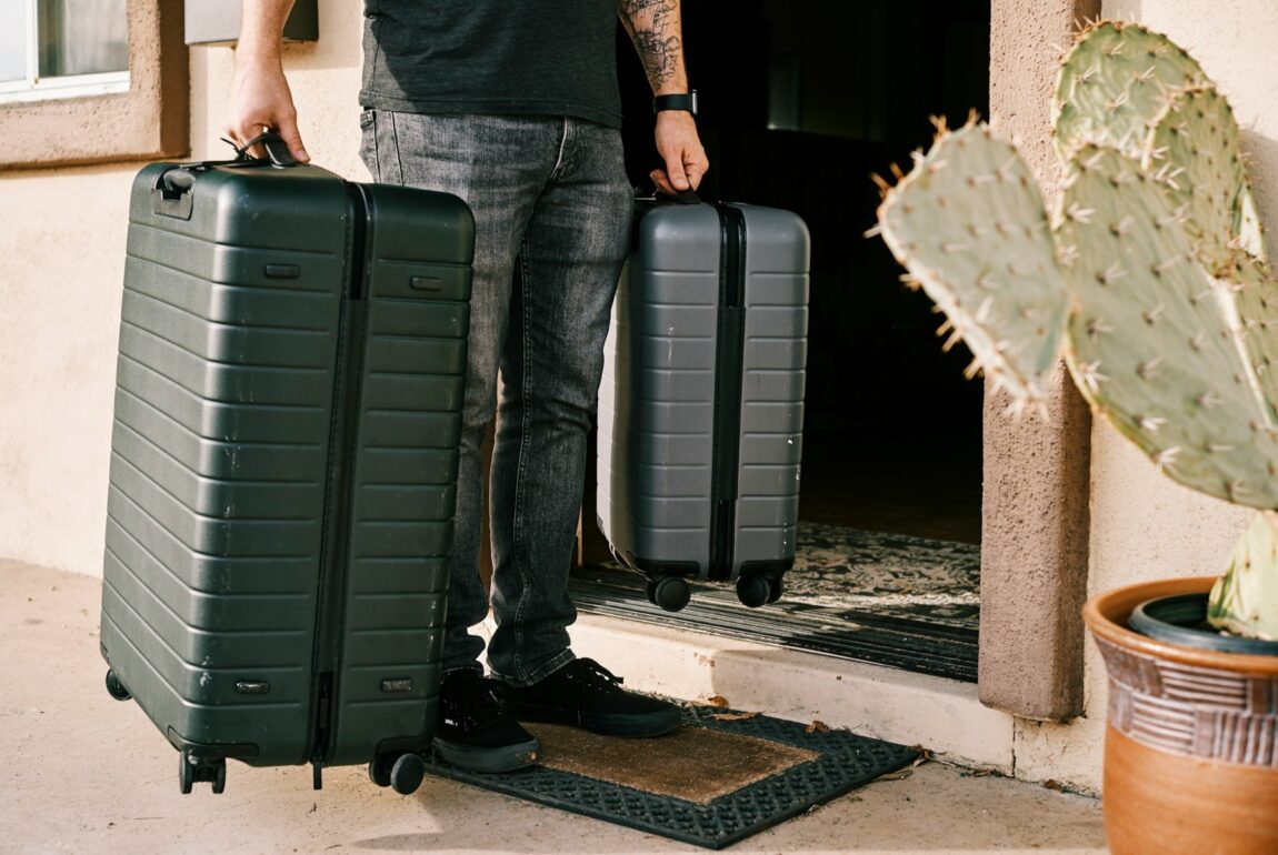 Traveler stepping out the front door with two suitcases