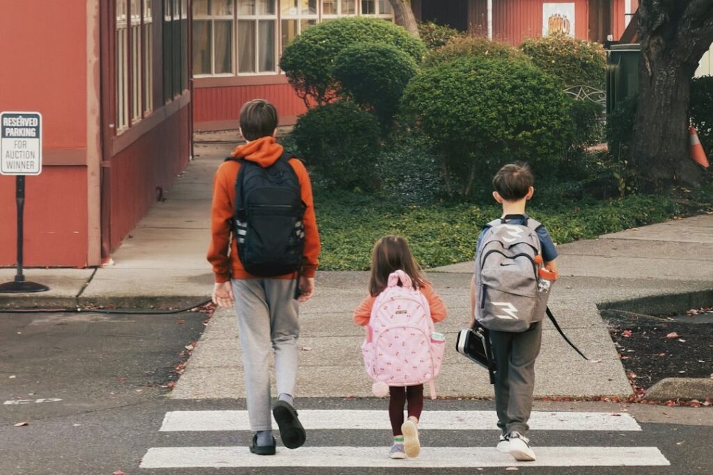 Three students with backpacks crossing the street to school