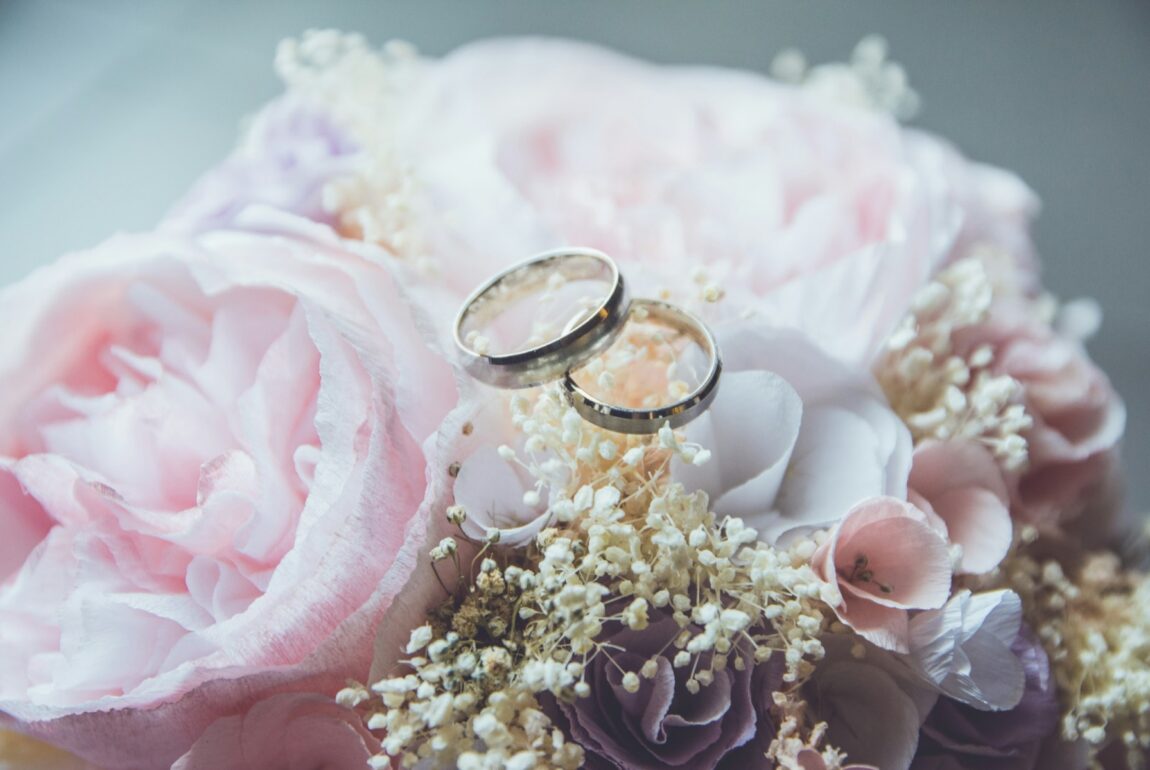 Two wedding rings resting on a pink rose bouquet